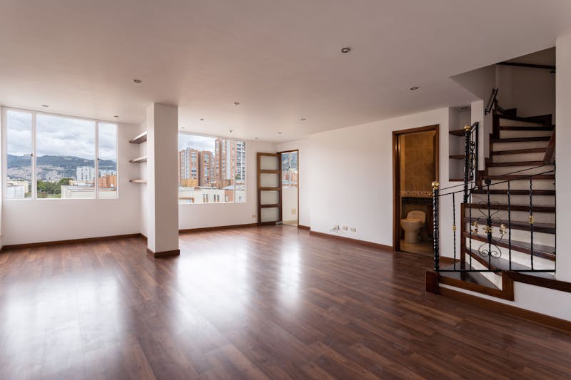 Bright living room with restored wooden floors, large windows and staircase